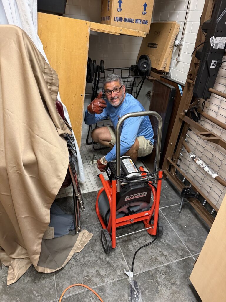 Plumber running a drain cleaning machine to clear a main line
