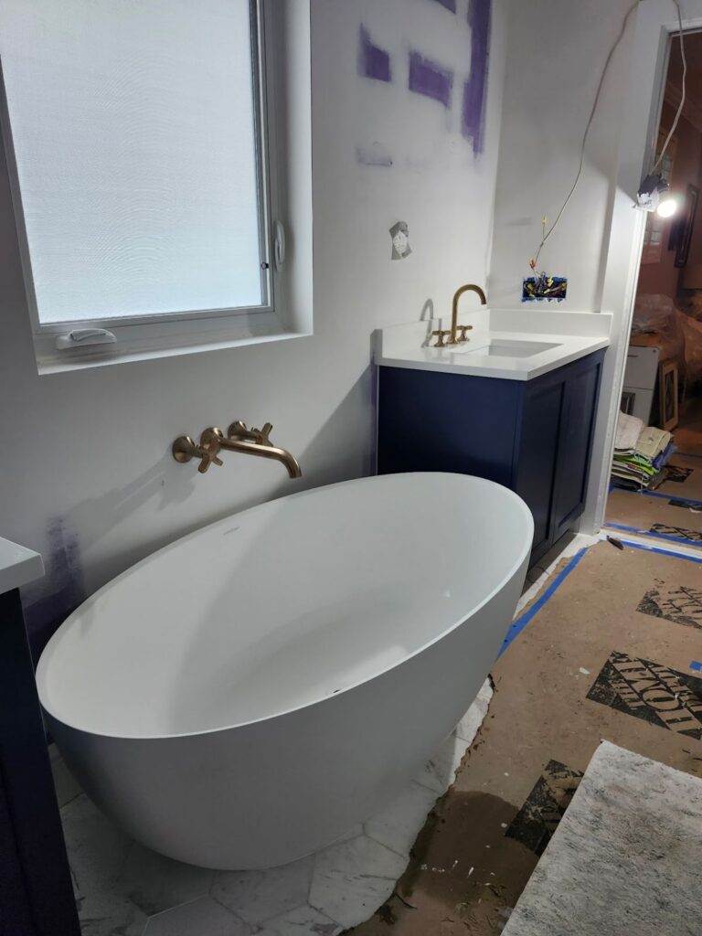 Freestanding soaking tub with a wall mounted brass faucet