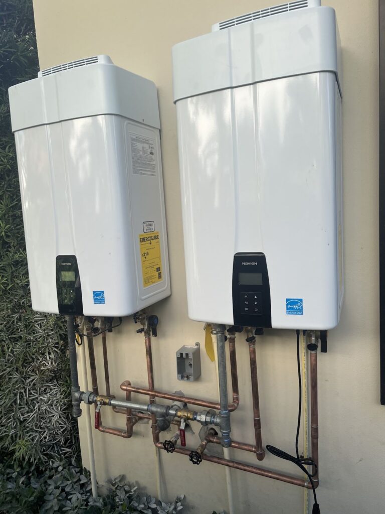 Two tankless water heaters installed on an exterior wall